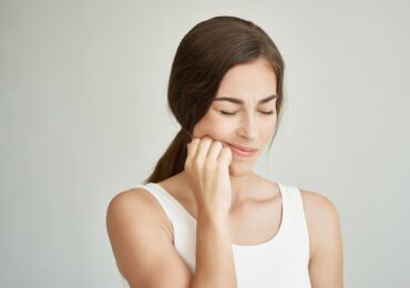 woman in white shirt experiencing toothache